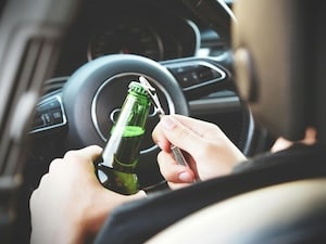 Moment of someone about to drink from a bottle inside a car.