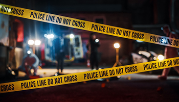 Yellow police tape on the ground outside a building